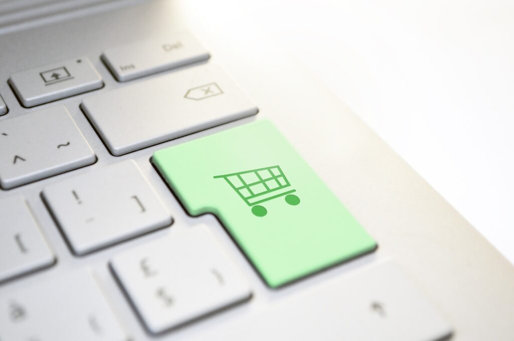 Nahaufnahme einer Laptop-Tastatur mit einer Enter taste auf der ein grüner Einkaufswagen als Icon zu erkennen ist